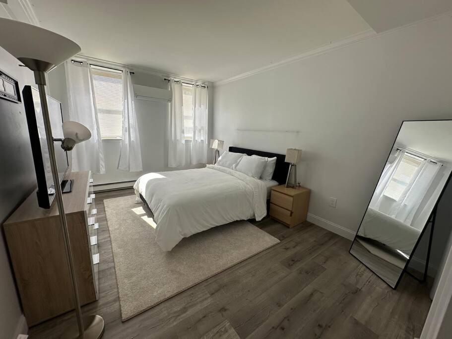 a white bedroom with a bed and a mirror at Cozy 1BR Condo in West Hartford