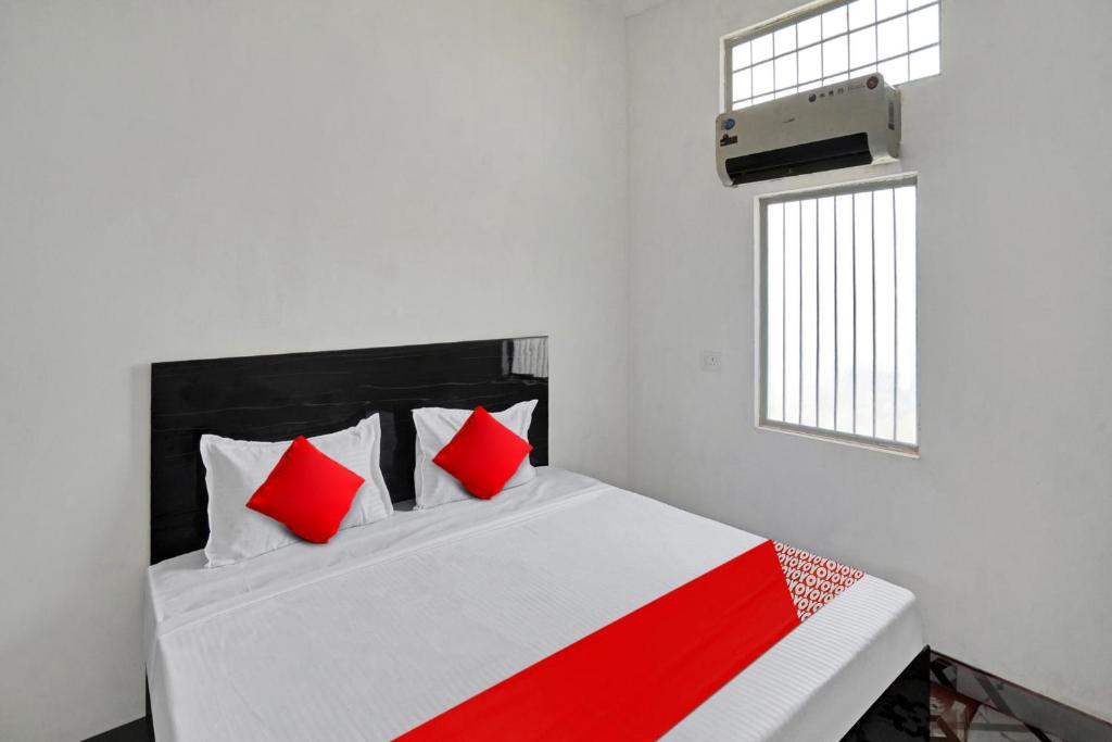OYO Flagship Amazing Inn في Murādnagar: غرفة نوم بسرير ومخدات حمراء ونافذة