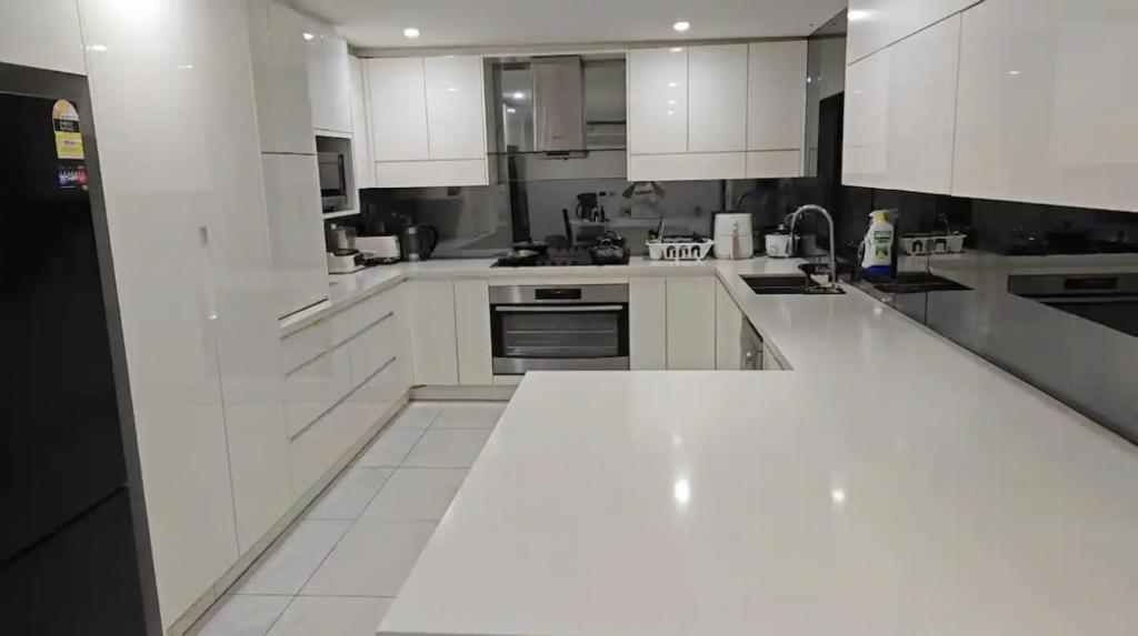 una gran cocina blanca con armarios y electrodomésticos blancos en Ground Floor Unit Near Liverpool, en Mount Pritchard