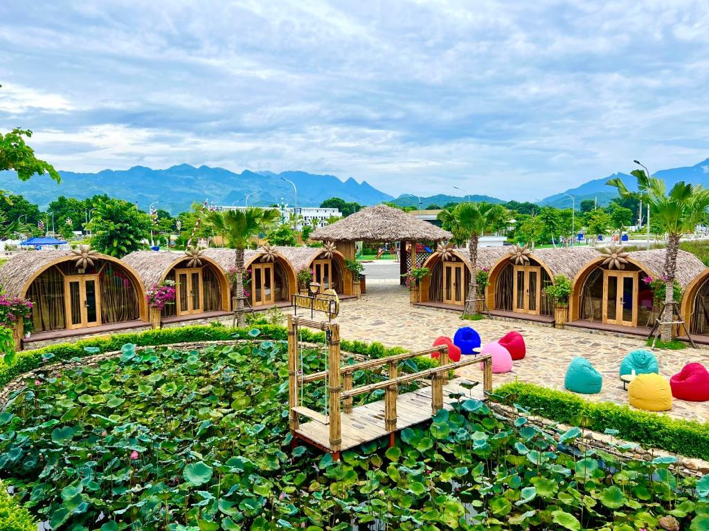 Khu Nghỉ Trải Nghiệm Golden Field في Bản Cong Na: حديقة بها جسر فوق بركة بها زنبق