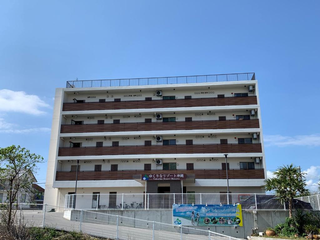 um grande edifício branco com uma cerca em frente em Yukurina Resort Okinawa em Motobu