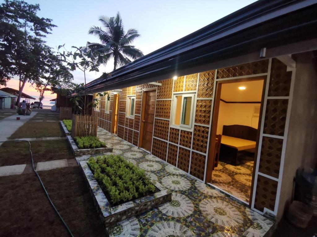 a house with a tiled facade with a garden at Tambayan Rooms and Cottages by SMS Hospitality in Carmen