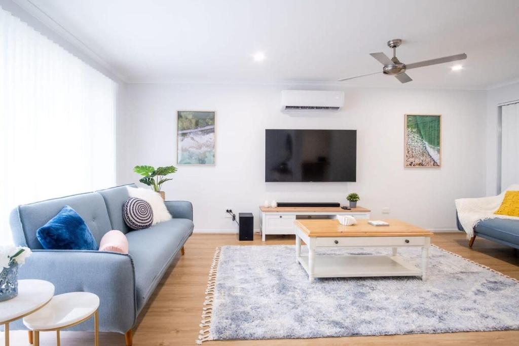 uma sala de estar com um sofá azul e uma televisão em Pet Friendly Battery Hill Home away from Home em Caloundra