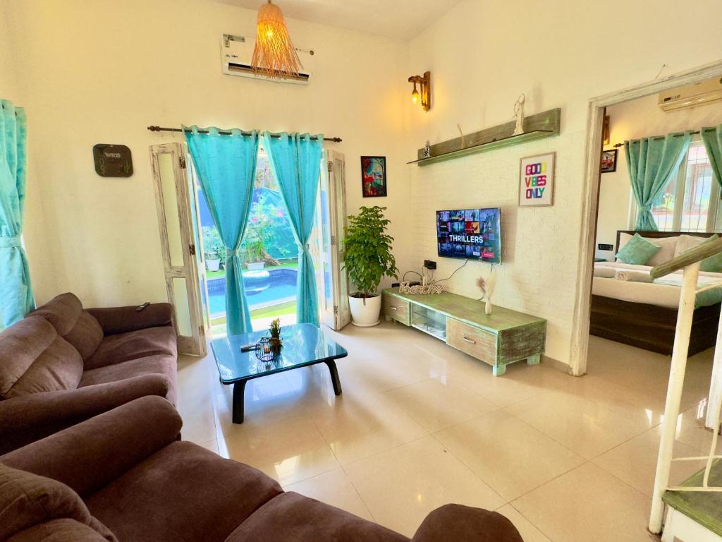 een woonkamer met een bank en een tafel bij Rustic Private Pool Villa # 8 by SAZJ Hospitality in Saligao