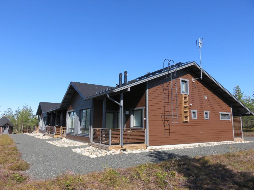 a home with a black roof and a wooden at Kotomänty Apartments in Ruka