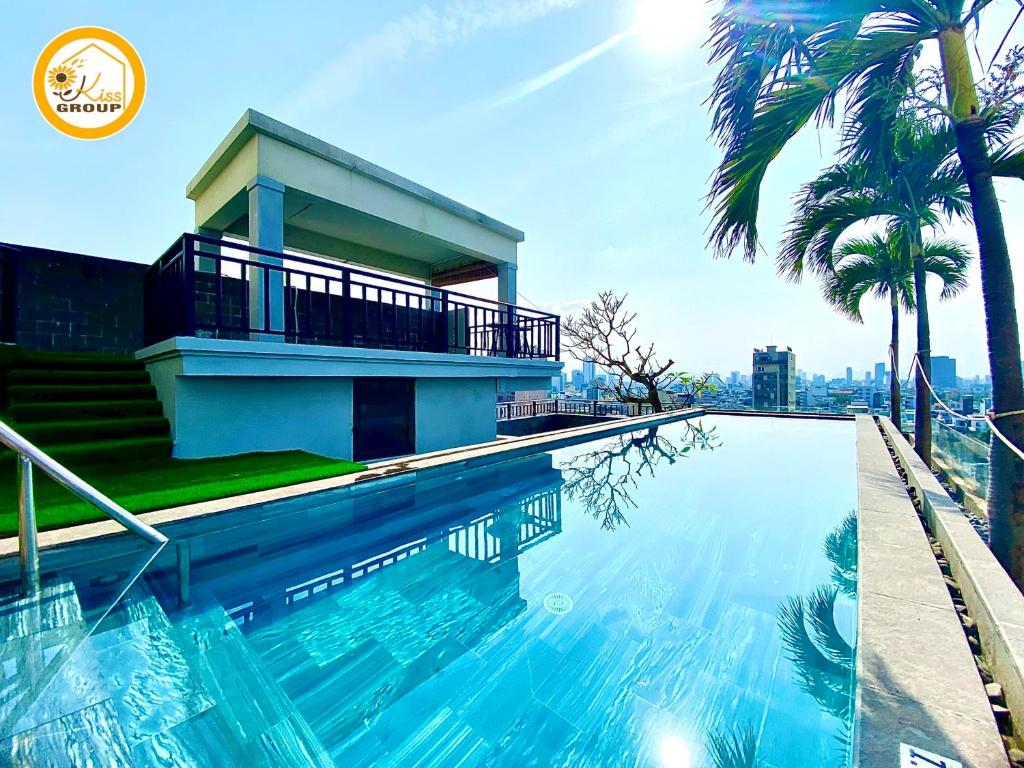 a swimming pool in front of a house with palm trees at Tokyo Boutique Front Beach Hotel in Danang