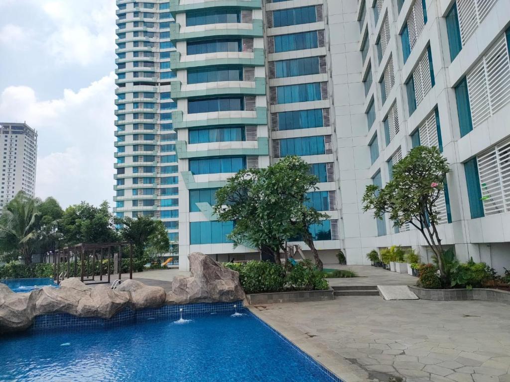 a swimming pool in front of a tall building at Apartemen Grand Kamala Lagoon by Abel Stay Luxury in Pekayon Satu