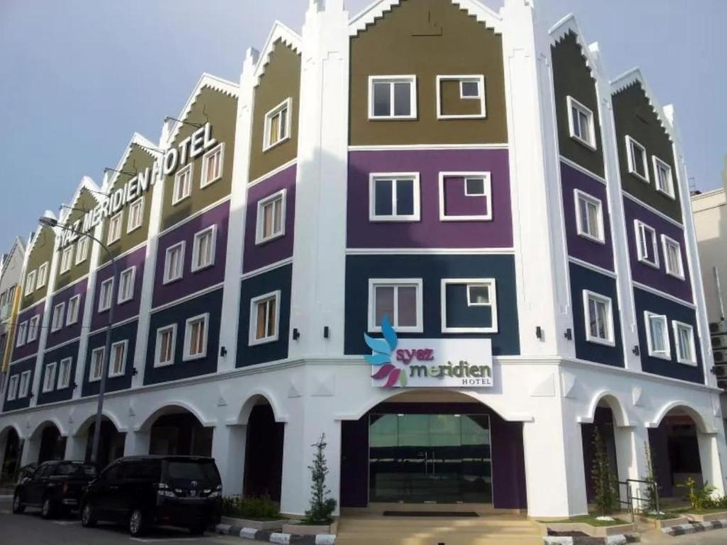 a large building with cars parked in front of it at Syaz Meridien Hotel in Melaka