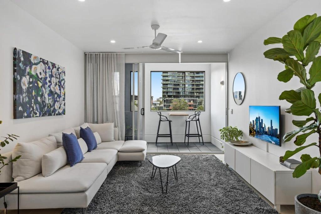 uma sala de estar com um sofá branco e almofadas azuis em Stellar Location With Parking Pool & Gym Access em Brisbane