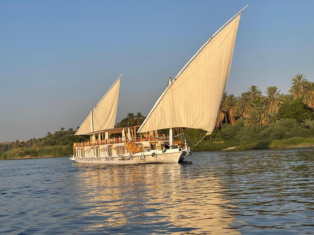 a white boat with two sails on the water at Dahabiya Nile Sailing - Mondays 4 Nights from Luxor - Fridays 3 Nights from Aswan in Luxor