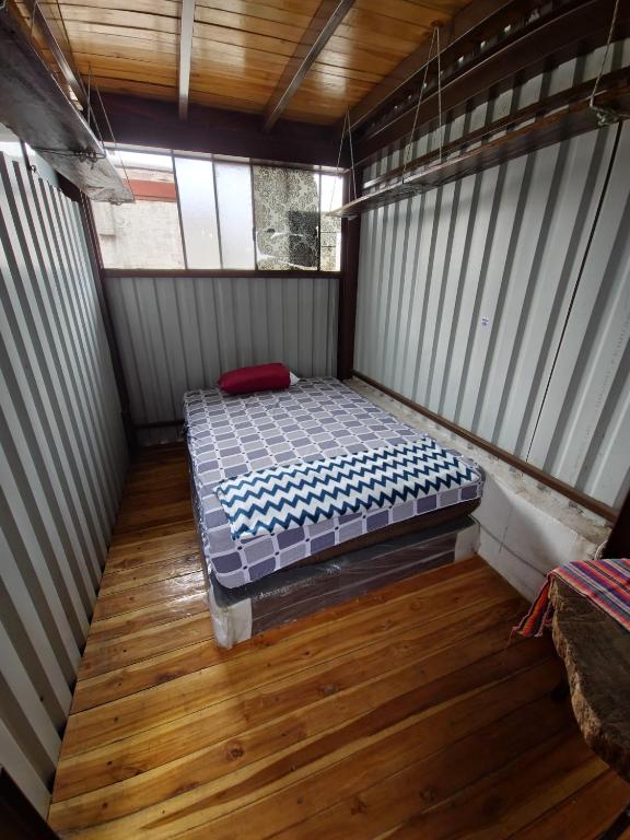 Cama pequeña en habitación con suelo de madera en Otto’s House, en Guatemala