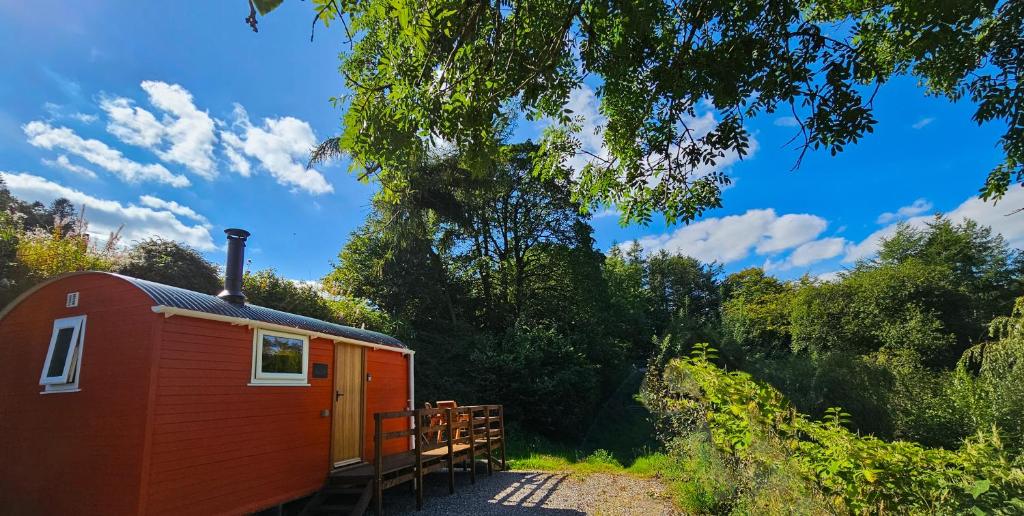 a red tiny house sitting in the woods at Red Kite at Wild Valley Huts in Oswestry