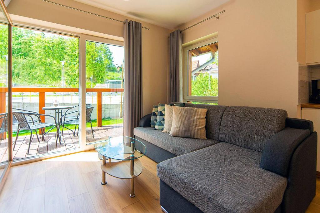 - un salon avec un canapé et une table en verre dans l'établissement Trevilles Apartamenty Mountain Cristal, à Szklarska Poręba