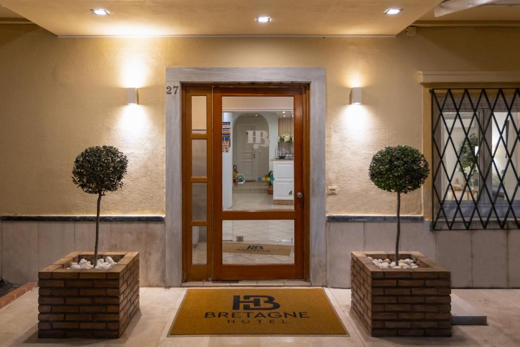 a lobby with two potted trees in front of a door at Hotel Bretagne in Corfu