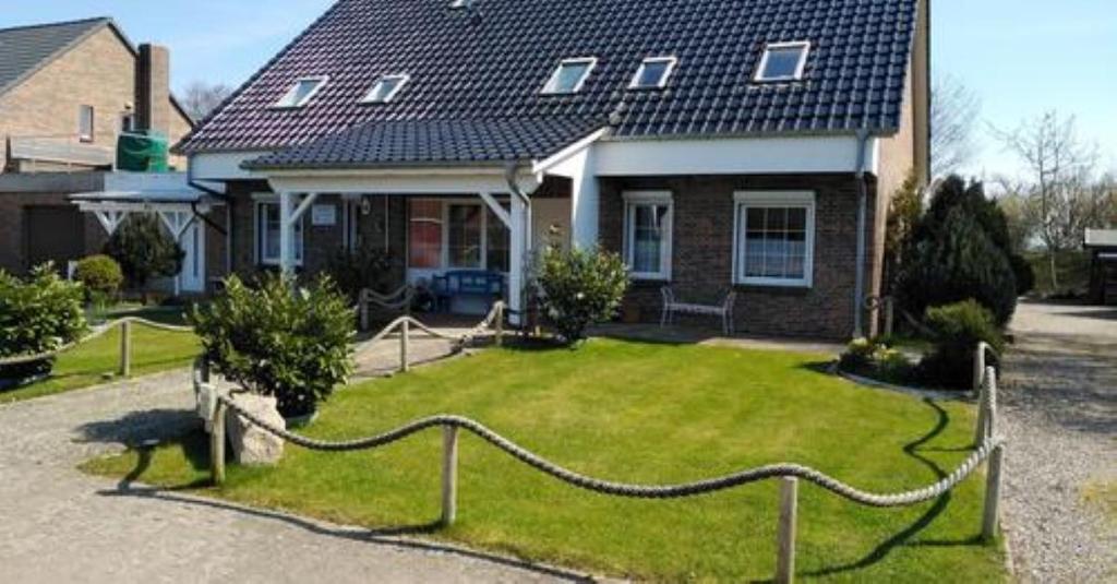 a house with a yard with a fence in front of it at Haus Rosi in Friedrichskoog-Spitz