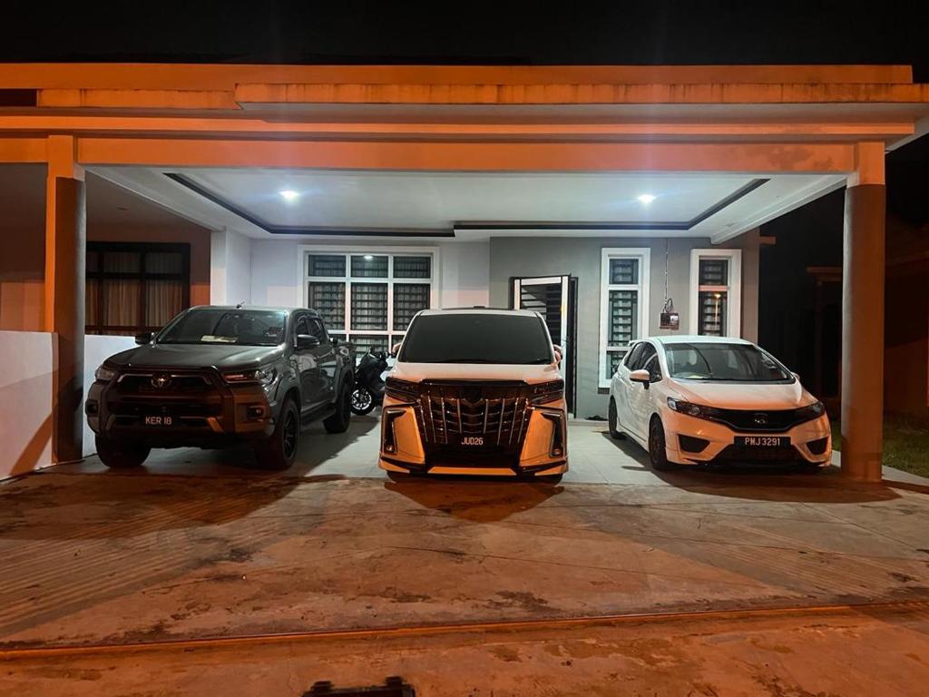 drei Autos parken in einer Garage in der Unterkunft Ziyyad's Homestay in Jitra