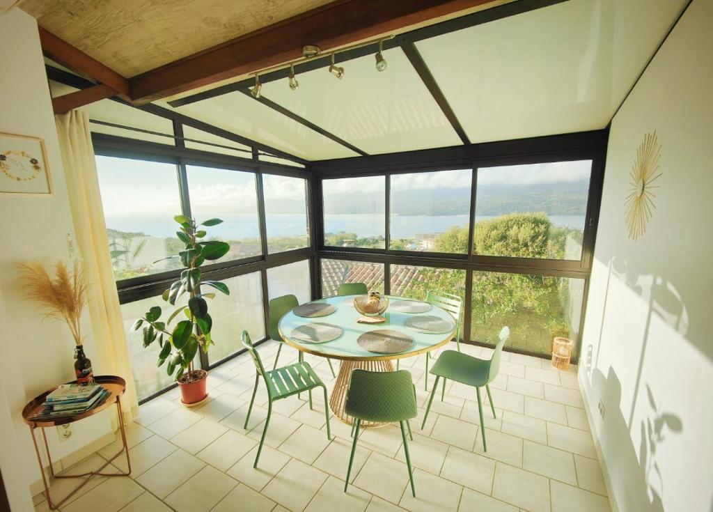 mesa y sillas en una habitación con ventana grande en Charmante petite maison magnifique vue mer en Propriano