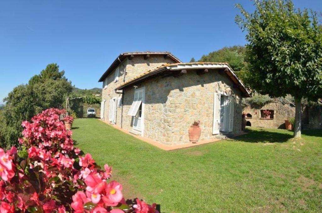 ein altes Steinhaus in einem Garten mit Blumen in der Unterkunft Ferienhaus für 12 Personen in Capannori, Toskana Provinz Lucca - b63292 in Petrognano
