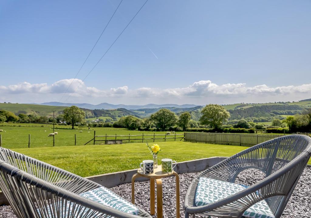two chairs sitting on a patio with a view of a field at Gladur in Cyffylliog