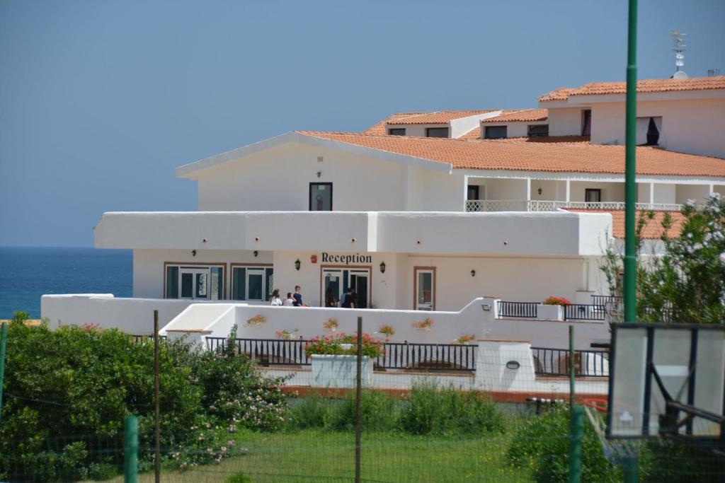 ein weißes Gebäude mit dem Ozean im Hintergrund in der Unterkunft Residence Cala del Mar - Happy Rentals in Marina di Sorso