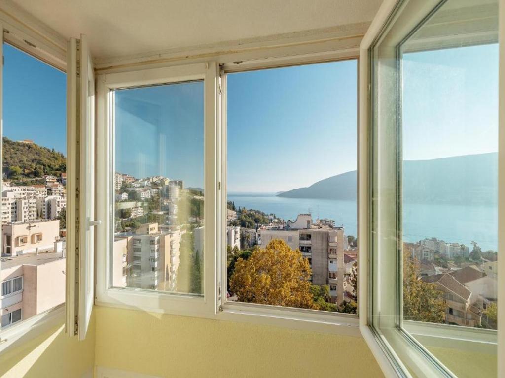 a room with three windows with a view of the city at Apartment Petit Jolie in Herceg-Novi
