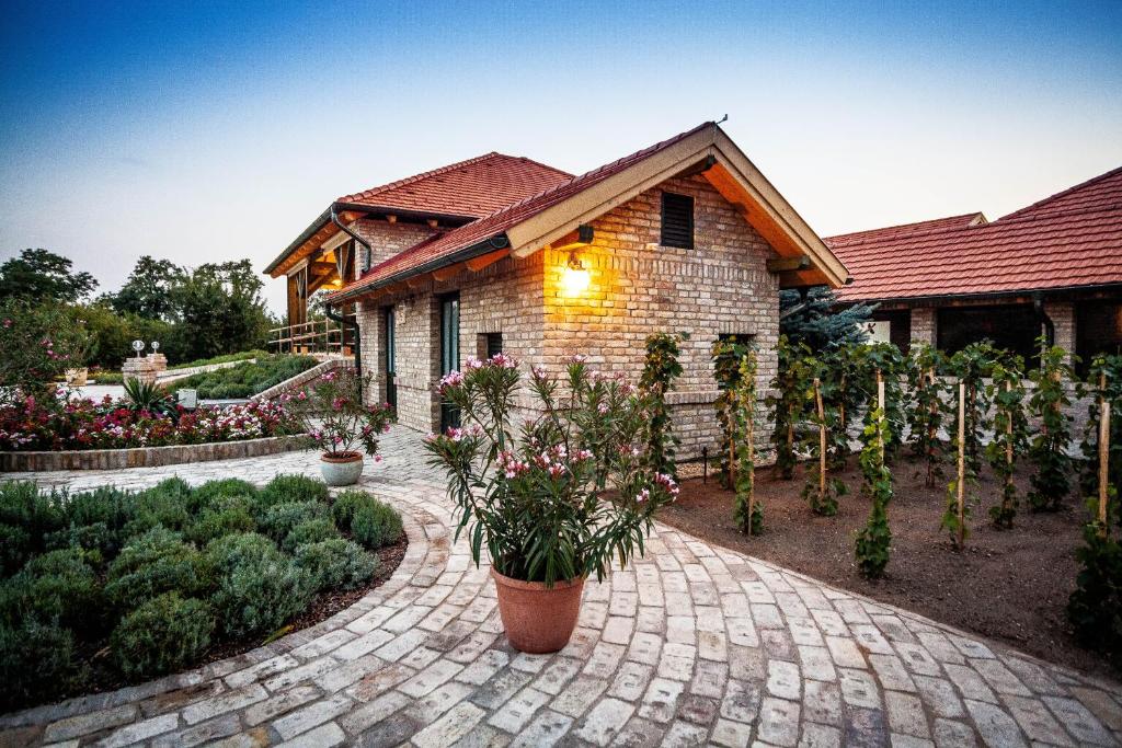 uma casa com um passadiço de tijolos em frente a um edifício em BÉNI family wine farm em Cegléd