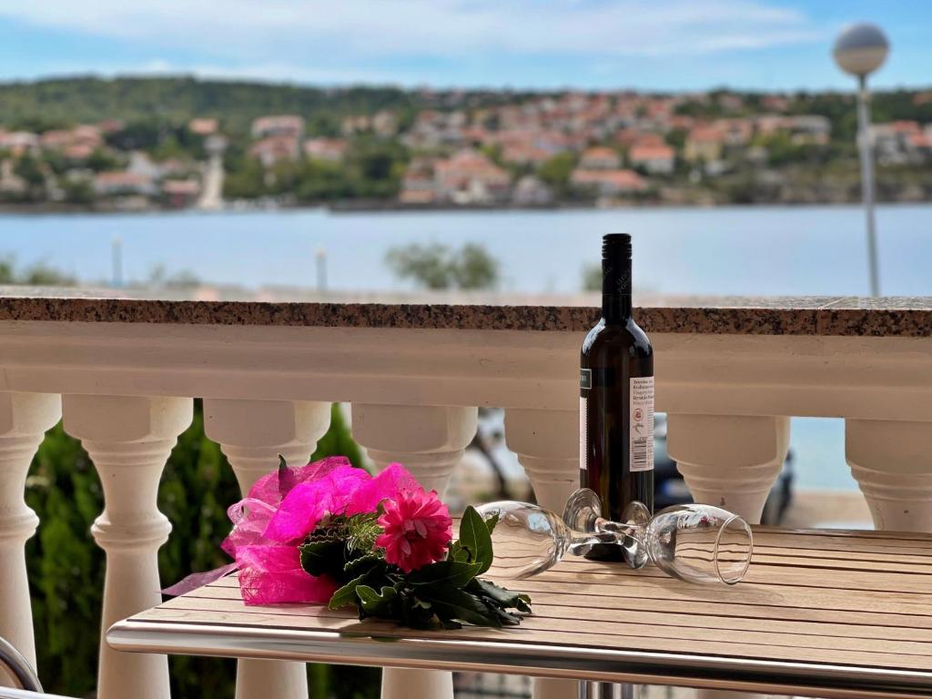 una botella de vino y una flor rosa sobre una mesa en Villa Tiha Lili, en Šilo