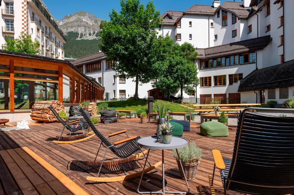 a patio with chairs and a table and a mountain at Hotel Schweizerhof Lenzerheide in Lenzerheide