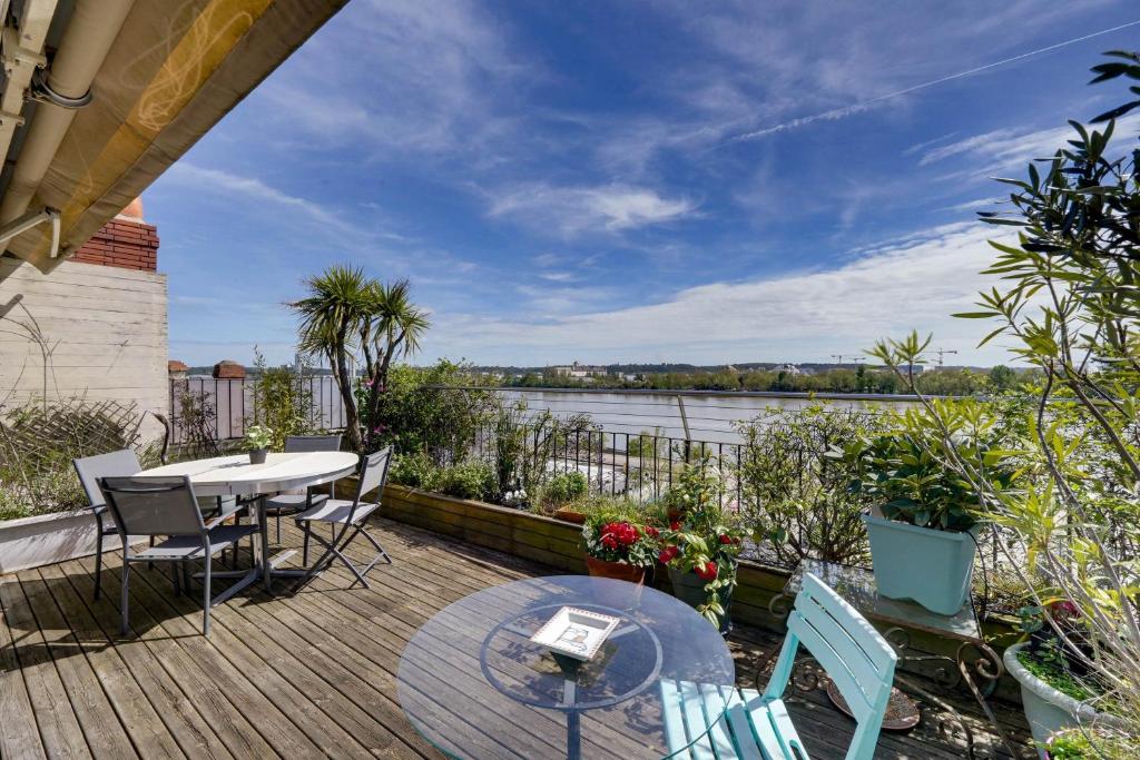 d'une terrasse avec une table et des chaises et une vue sur la rivière. dans l'établissement Le Renversant - Appartement d'exception de 160m2, à Bordeaux