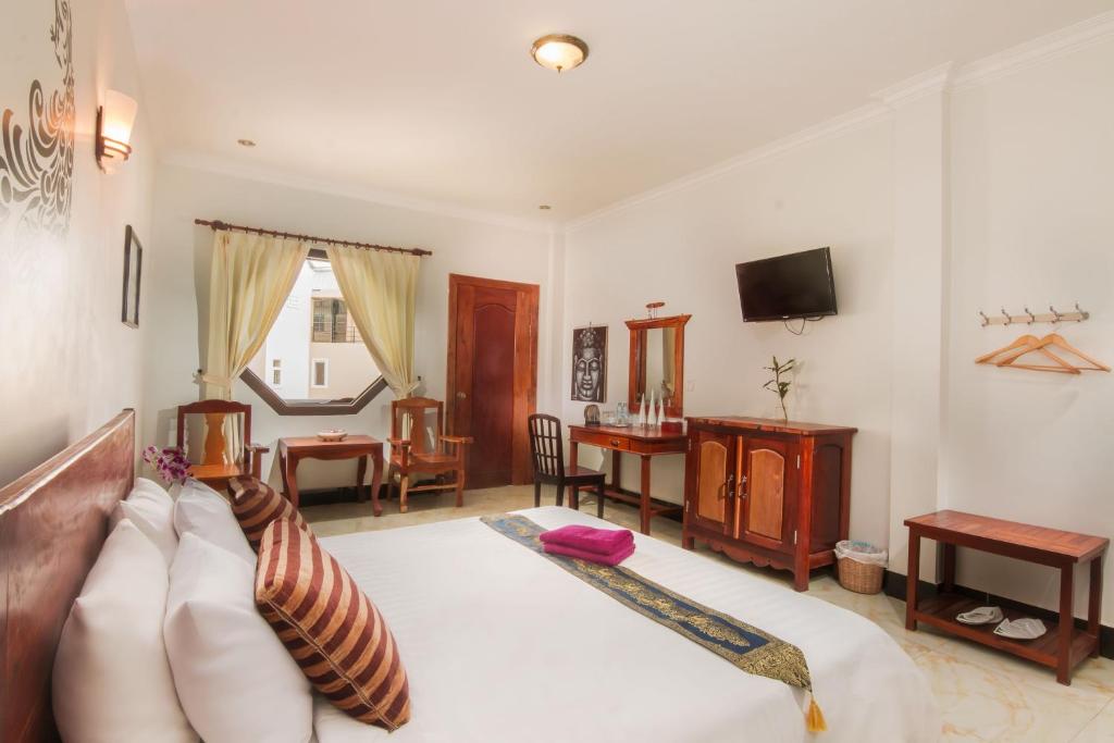Angkor Udom Guesthouse في سيام ريب: غرفة معيشة فيها سرير وتلفزيون