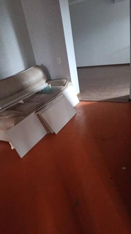 Cette chambre dispose d'un sol rouge et d'un canapé avec des papiers. dans l'établissement Ulan Guest House, à Akkyya