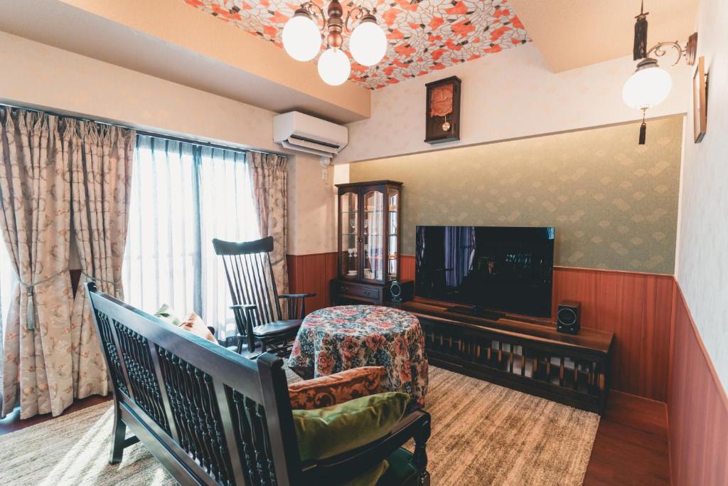 ein Wohnzimmer mit einem TV, einem Sofa und einem Stuhl in der Unterkunft ルグランみしま in Hamamatsu