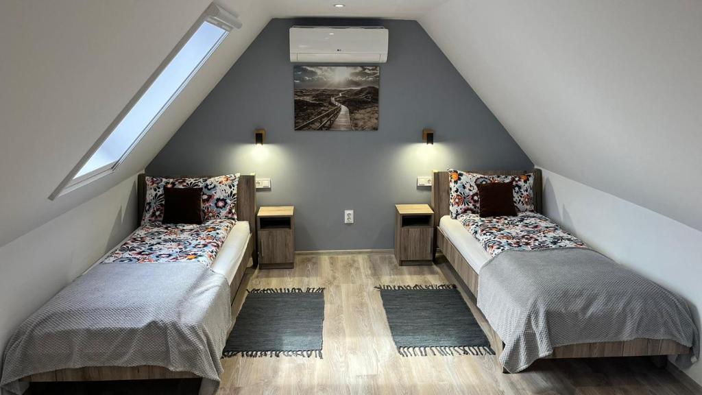 a attic room with two beds and a window at Habitat of Dreams in Makó