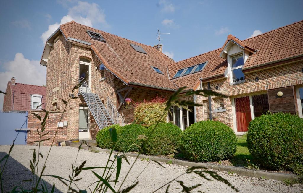 a brick house with bushes in front of it at Les chambres du Moulin in Arleux-du-Nord
