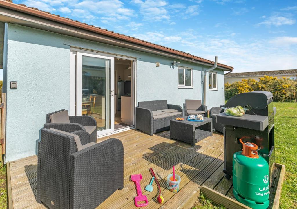 a deck with chairs and a grill on a house at Lantic Surf in St Merryn