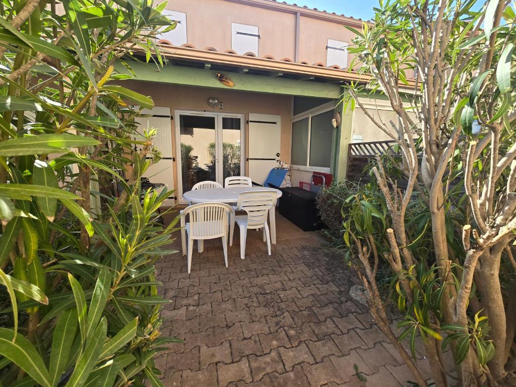 un patio avec une table et des chaises devant une maison dans l'établissement L'échapée Belle - Villa, résidence avec piscine et stationnement à proximité de la mer, à Vendres
