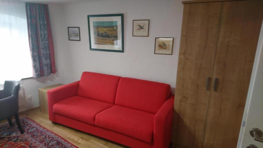 un sofá rojo en una sala de estar con puerta en Appartement 2 Personen Hallein bei Salzburg en Hallein