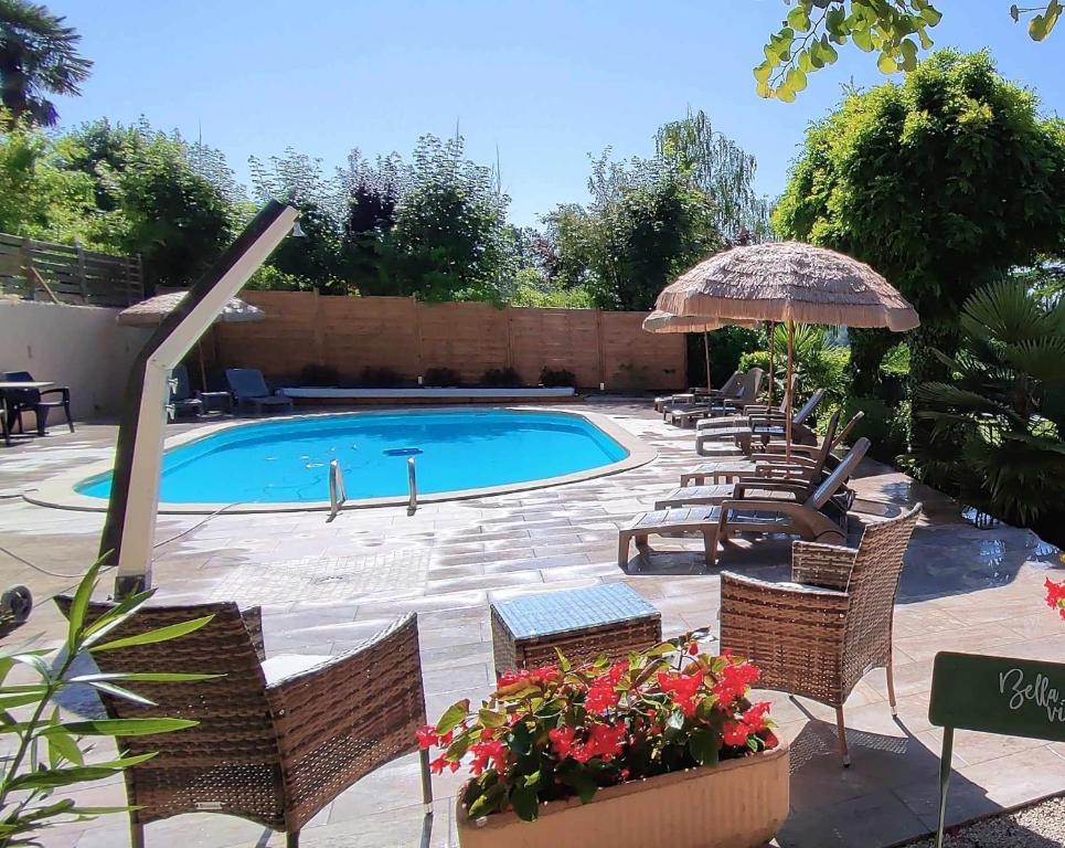 een zwembad met stoelen en een parasol bij Hotel Belle Vue in Souillac