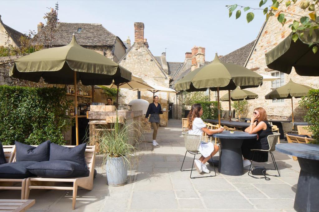 duas mulheres sentadas à mesa num pátio com guarda-sóis em BULL Burford em Burford