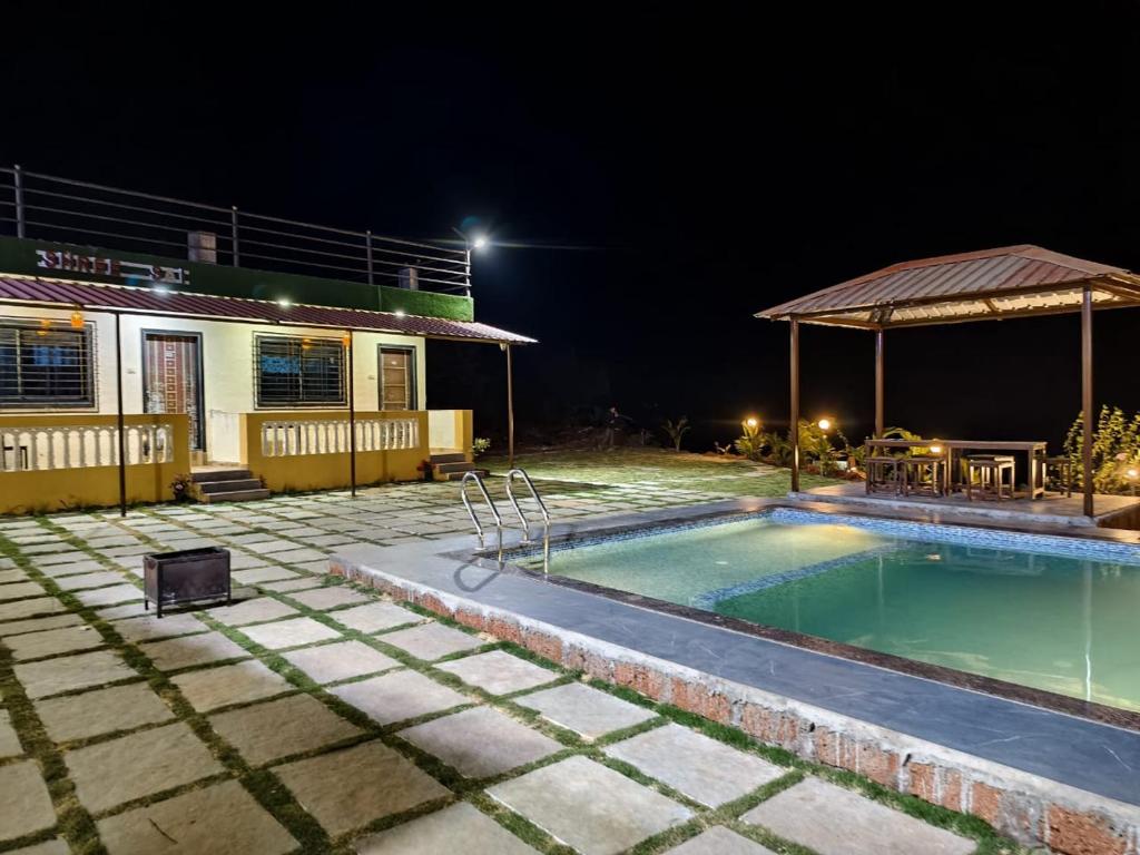 a house with a swimming pool at night at Shayadri Farmhouse in Mahabaleshwar