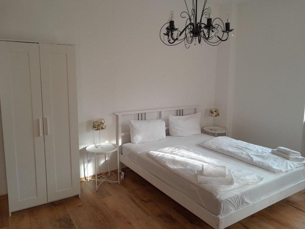 a white bedroom with a bed and a chandelier at B10-LINDE in Baden-Baden