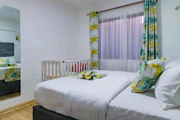 ein Schlafzimmer mit einem großen weißen Bett und einem Fenster in der Unterkunft Naivasha Wonderland Resort in Naivasha