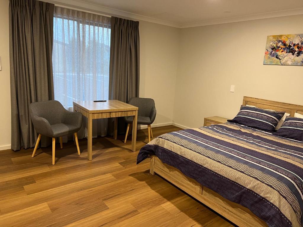 Schlafzimmer mit einem Bett, einem Tisch und Stühlen in der Unterkunft The Morrison Motel in Swan View