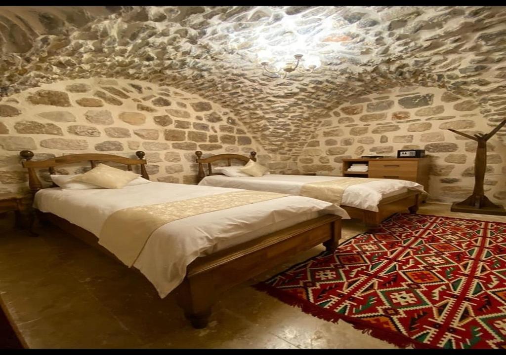 Habitación con 2 camas y pared de piedra. en Old City Tourism en Mardin