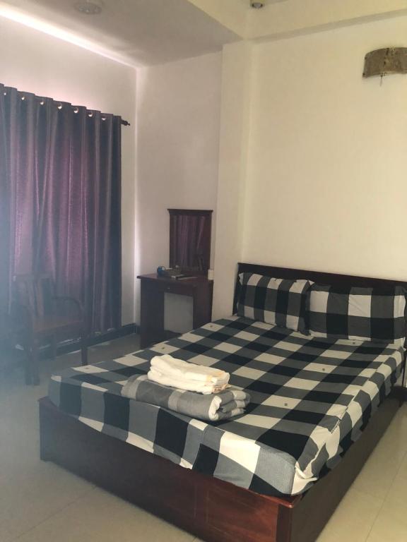 1 dormitorio con cama a cuadros en blanco y negro en Khách sạn thái bảo, en Thôn Mỹ Phước