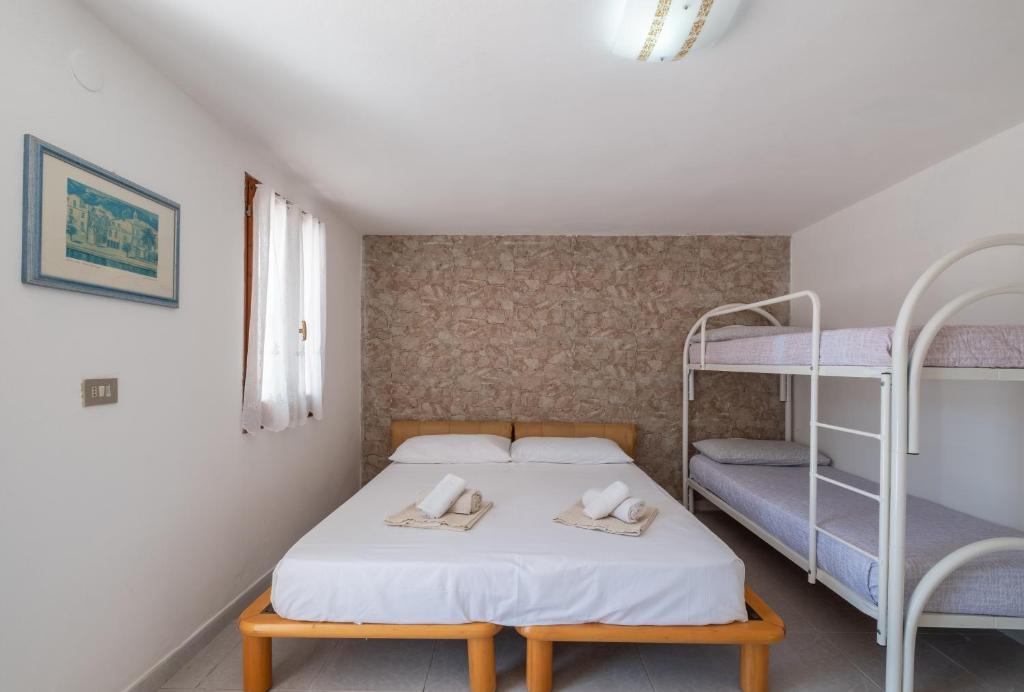 a bedroom with a bed with two bunk beds at Camera in Villa, 1 minuto da Porto Pino in Porto Pino
