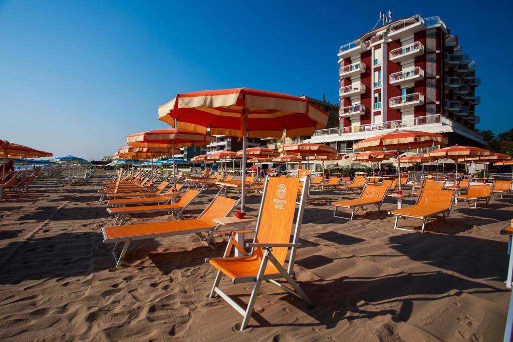 チェゼナーティコにあるHotel Sportingのビーチの椅子とパラソルの束