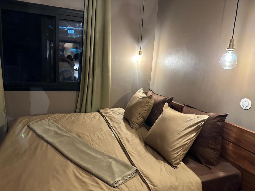 een slaapkamer met een bed met kussens en 2 verlichting bij NH (Njato Hôtel) in Antananarivo