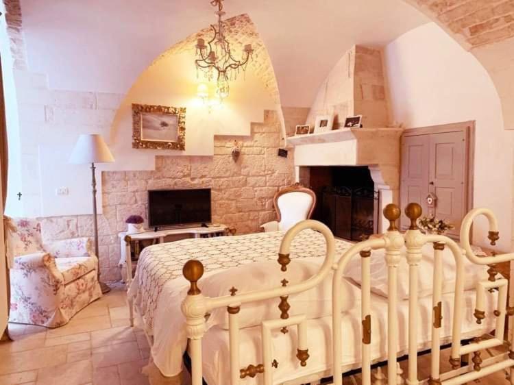 a bedroom with a white bed and a fireplace at La Neviera dell'Arco in Martina Franca