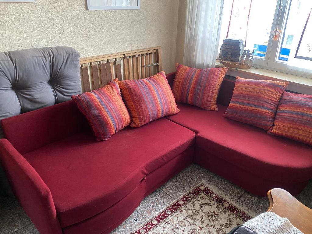 ein rotes Sofa mit Kissen darauf im Wohnzimmer in der Unterkunft Nördlingen im Ries - Königsbergerstr. - kleines Gästezimmerchen in Nördlingen